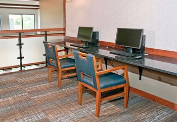 A computer desk with two computer monitors and two chairs
